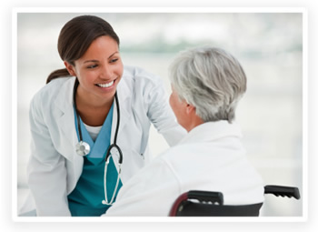 A smiling doctor leans down to talk to a patient in a wheelchair