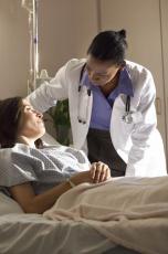 Fotografía de una doctora hablando con una paciente acostada en la cama de hospital
