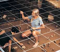 (photo) Archeologists under a grid measure the position of artifacts with a plumb bob. Use prohibited without permission.