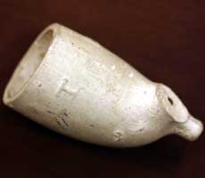 (photo) Ceramic tobacco pipe bowl with an embossed maker's mark. (NPS)