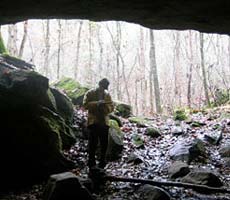 (photo) Geoarcheologist scouts a cave. (Midwest Archeological Center)