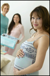 A pregnant woman, with two other women in the background.