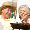 An older couple grilling hot dogs