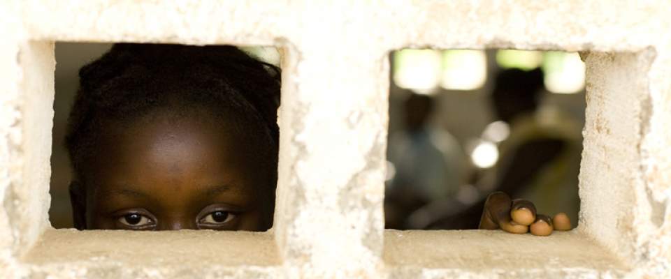 A 13-year-old former sex worker peers out the window of a school in Sierra Leone.