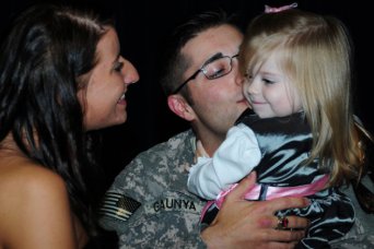 Staff Sgt. Jeffrey Gaunya, 597th Ordnance Maintenance Co., kisses his daughter, Celine, and reunites with his wife, Sabrina, during a redeployment ceremony at the Spiritual Life Center Oct. 8. Thirteen Soldiers from the 164th Theater Airfield Operations Group returned to Fort Rucker after an eight-month deployment to Afghanistan.