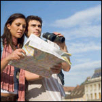 Una mujer mirando un mapa y un hombre aguantando unos binoculares