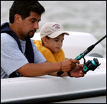 padre e hijo con el equipo de seguridad adecuado para pescar en bote