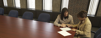 Photo of 2 women sitting at a conference table