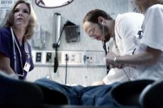 Photograph of a male doctor and female nurses examining a patient