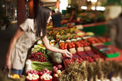 photo of a woman looking at fruits and vegetables in a store