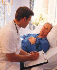 Fotografía de un doctor sentado al lado de la cama de un paciente