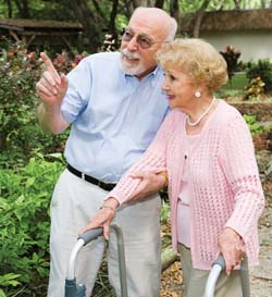 A man walking with a woman using a walker