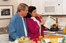 Photograph of a man and a woman reading a food label in the kitchen