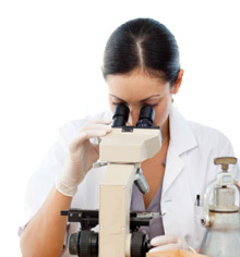 Photo of a lab worker looking through a microscope