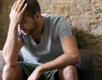 Photo: Depressed man with hand on forehead