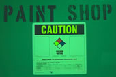 Photo of a warning sign on a wall that reads paint shop