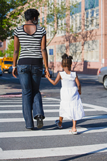 Mother and daughter crossing street in crosswalk