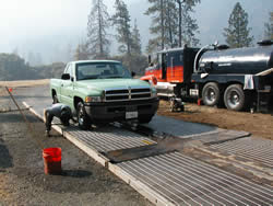 man washing the underside of a Forest Service truck with a power sprayer.