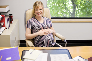 pregnant woman sitting at a desk smiling