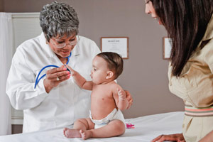 a doctor examining a baby while the mother watches