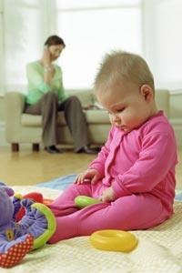 una mujer hablando por teléfono mientras un bebé juega en el suelo