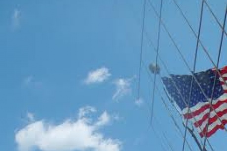 American Flag reflecting off of building. Blue sky and clouds in the background. 