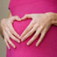 Manos de una mujer embarazada formando un corazón