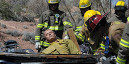 A group of firefighters pulls a mannequin out of a wrecked vehicle.