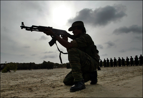 A woman fighter of the Tamil Tigers takes a shooting position in Sri Lanka in July 2007. AP Photo.