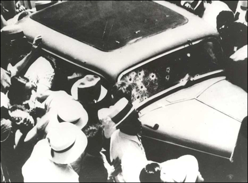      A crowd gathers around Bonnie and Clyde's bullet-ridden sedan not long after the fatal ambush.