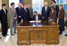 Secretary Locke at far left watches as President Obama signs Act. Click for larger image.