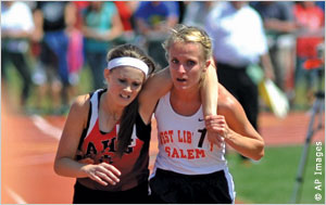 True sportsmanship: Meghan Vogel (right) carries competitor Arden McMath to the finish line in a 3,200-meter race, making sure that McMath crosses first.