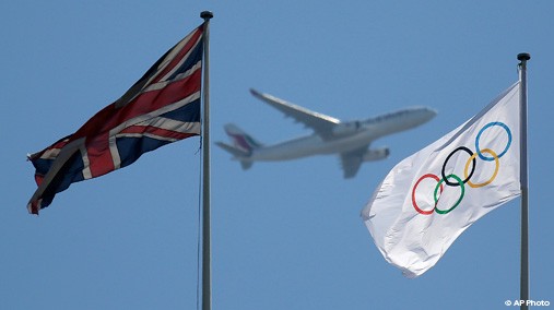 A passenger jet is framed between British and Olympic flags as it flies over London, July 23, 2012. Opening ceremonies for the 2012 London Olympics are scheduled for Friday, July 27. [AP Photo]