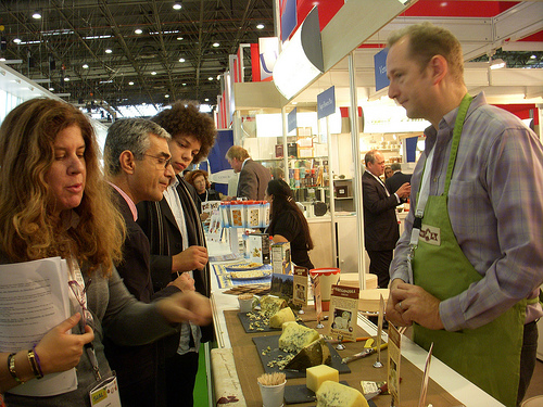 Trade visitors sample a variety of cheeses at the Rogue Creamery stand in the USA Pavilion. Rogue Creamery, an artisan cheese company, is dedicated to sustainability and the art and tradition of making the world's finest handmade cheese.