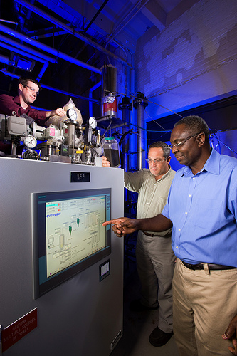 ARS chemical engineer Akwasi Boateng (right) and mechanical engineer Neil Goldberg (center) adjust pyrolysis process conditions while chemist Charles Mullen (left) loads the reactor with bioenergy feedstock. 