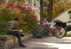 Bikes in rack with student studying on ledge