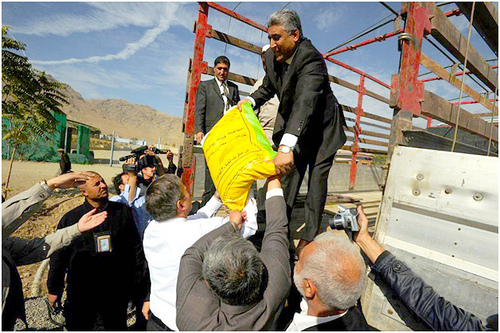 U.S. Ambassador to Afghanistan Karl Eikenberry (front in white) and Afghan Agriculture Minister Asif Rahimi (on truck) load seed At Badam Bagh Farm in Kabul.