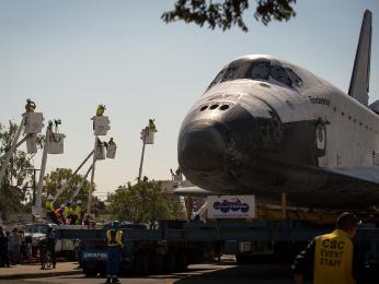 Cable technicians raise their cherry pickers watch and photograph the space shuttle Endeavour as it is maneuvered through the streets of Inglewood, Calif., on its way to its new home at the California Science Center, on Oct. 13, 2012. Endeavour, built as a replacement for space shuttle Challenger, c