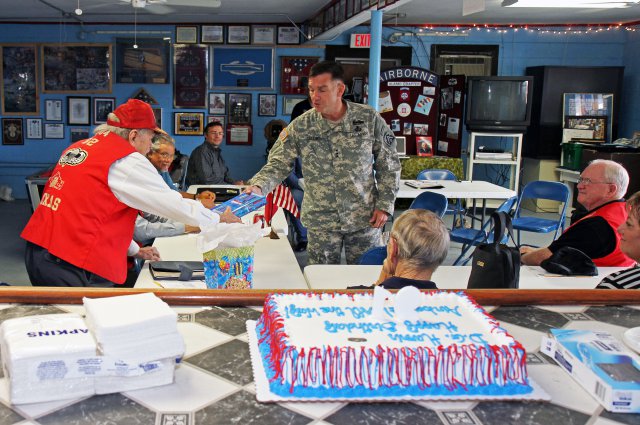 Lt. Gen. William Caldwell IV, commanding general, U.S. Army North, and senior commander, Fort Sam Houston, Texas, and Camp Bullis, presents a 91st birthday gift to World War II veteran Darrell G. Harris, Oct. 15, 2012. Harris made three combat jumps at Sicily, Salerno and Nijmegen during World War II and a beach landing at Anzio. The gift, "September Hope: The American side of a Bridge Too Far," by John C. McManus, discusses the American perspective during Operation Market-Garden, a World War II offensive that Harris participated in.
