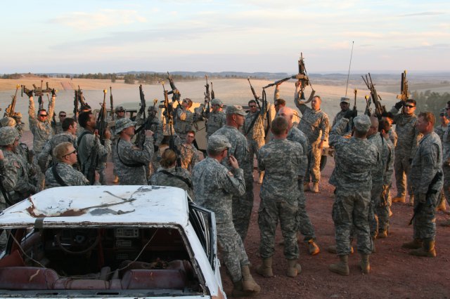 Soldiers from 663rd Ordnance Company, 242nd Explosive Ordnance Disposal Battalion, 71st Ordnance Group (EOD), raise their weapons into the air at the end of an intense day training at Camp Guernsey, Wyo. The company trained at the camp for 18 days.