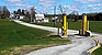 Morses Line today – looking from the U.S. border inspection station northward on Morses Line Road (Vt. Route 235.) The one-story white building on the right side of the road with blue sign on the roof is the Morses Line, Province Québec border inspection station, constructed in 1952. The farm complex on the near right side of Morses Line Road, the border station, and the Rainville farm survive. There is little else left of the once thriving hamlet of Morses Line – except the name.