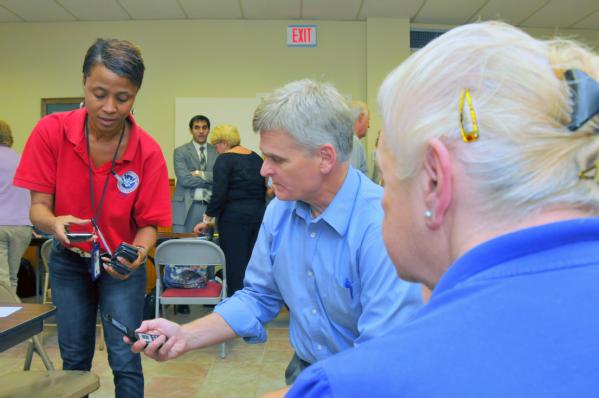 French Settlement, La., Sep. 5, 2012 -- Applicant Services Specialists, Teia Beaulieu, left, and U.S. Congressman Bill Cassidy, M.D., Sixth District of Louisiana, compare signal strength on their cell phone while helping a woman affect by Hurricane Isaac call to register for assistance. Congressman Cassidy requested that FEMA representatives attend the town hall meeting in French Settlement, La. to take questions and provided information to the community. 