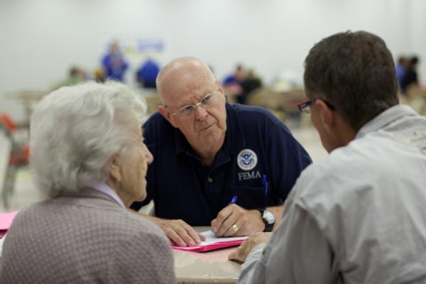 Federal Emergency Management Agency employee, K. Ordway assists a disaster survivor at the FEMA/State Disaster Recovery Center at the Auditorium in South Minot, North Dakota.