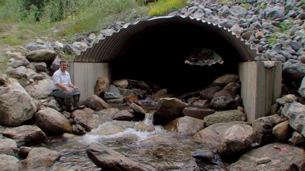Rochester, Vt., July 29, 2012 -- U.S. Forest Service Civil Engineer Brian Austin sits outside a culvert on a tributary running through the Moosalamoo National Recreation Area in Arlington, Vermont. Tropical Storm Irene-damaged culverts in Rochester, Vermont will be similarly reconstructed, using rocks and sand to simulate a natural fish passage. 