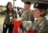 Red Cross woman talking to military service man and woman at an event