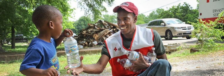 Red Cross disaster responding giving a bottle of water to a little boy