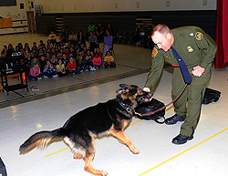 Border Patrol agent Christopher Harvey demonstrates at Round Hill Elementary School with Hoss, a CBP canine, who is trained to detect large amounts of currency.