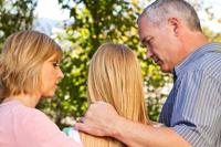 Two parents comfort their daughter