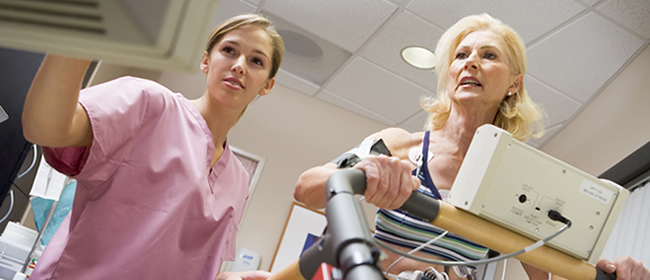 Nurse and female patient undergoing stress test on treadmill