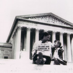 Mother and daughter sitting on the U.S. Supreme Court building steps holding a newspaper with a headline about the end of segregation i n public schools